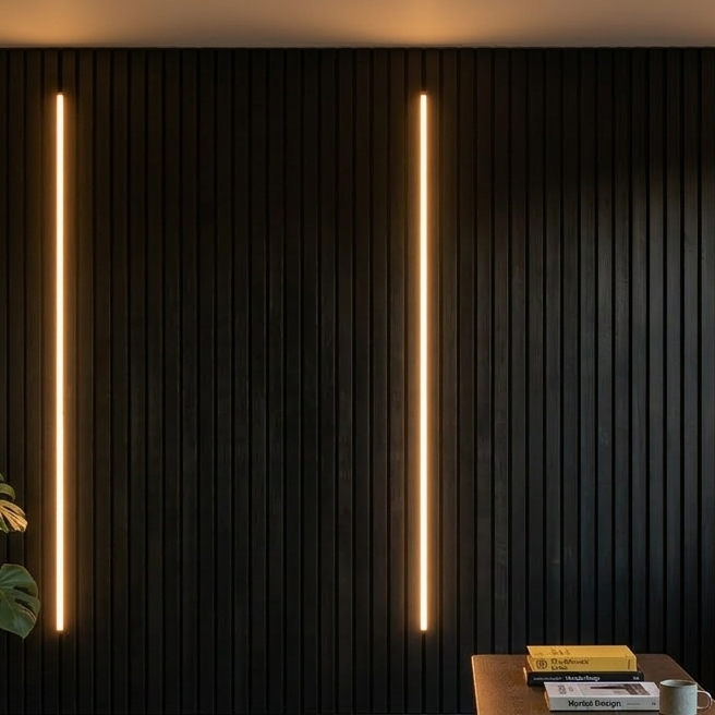 Two vertical light strips on a dark textured wall with a table and books in the foreground.