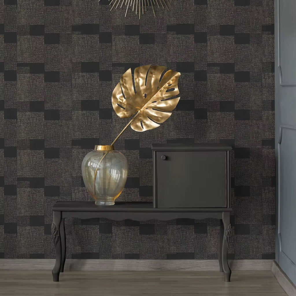 Decorative interior setting with a gold leaf sculpture, vase, and mirror on a dark patterned wall.