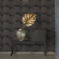 Decorative interior setting with a gold leaf sculpture, vase, and mirror on a dark patterned wall.