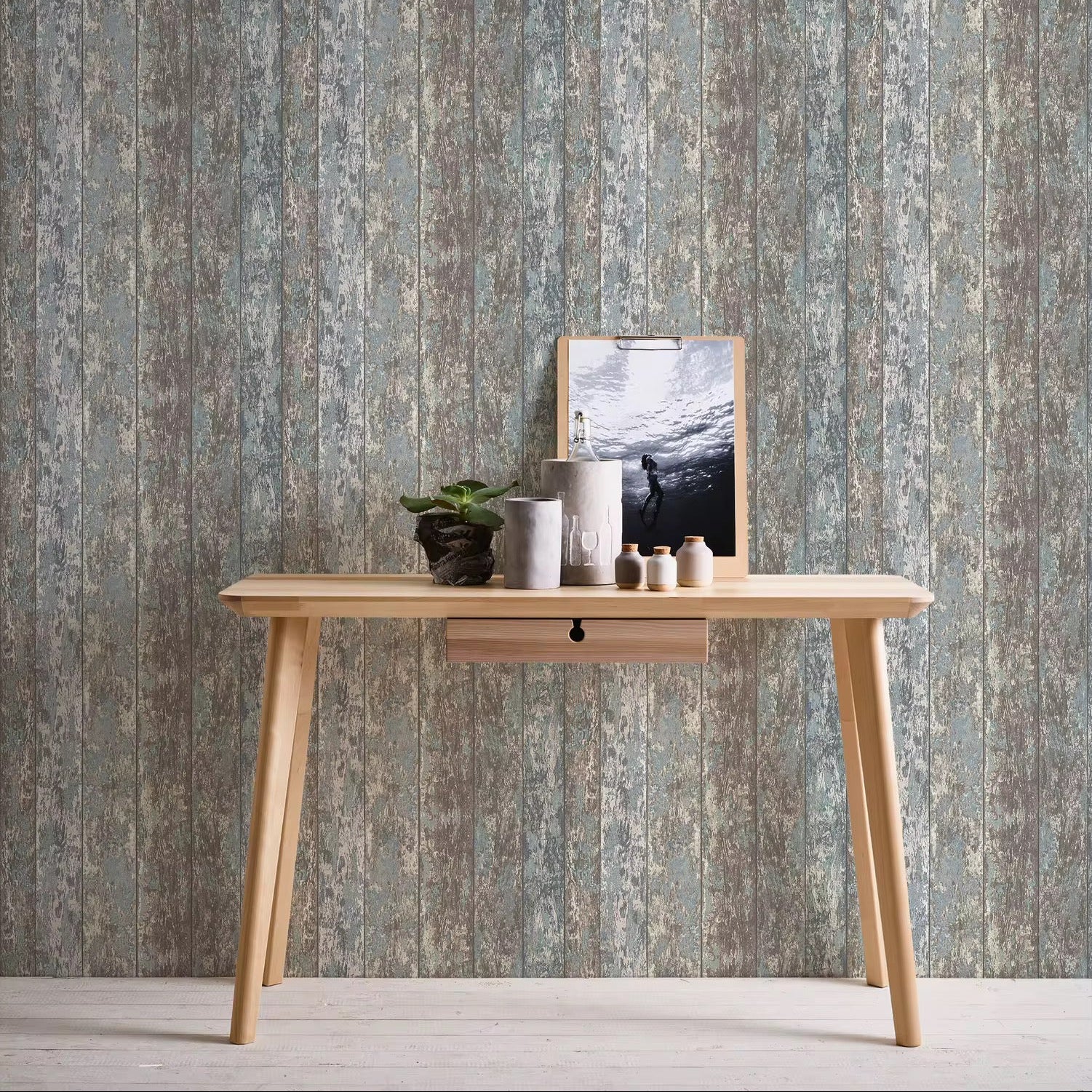 Wooden desk with decorative items against a striped wallpaper background