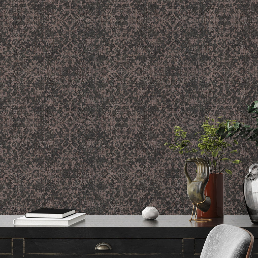 Decorative wallpaper with a subtle pattern on a wall behind a dark wooden desk.