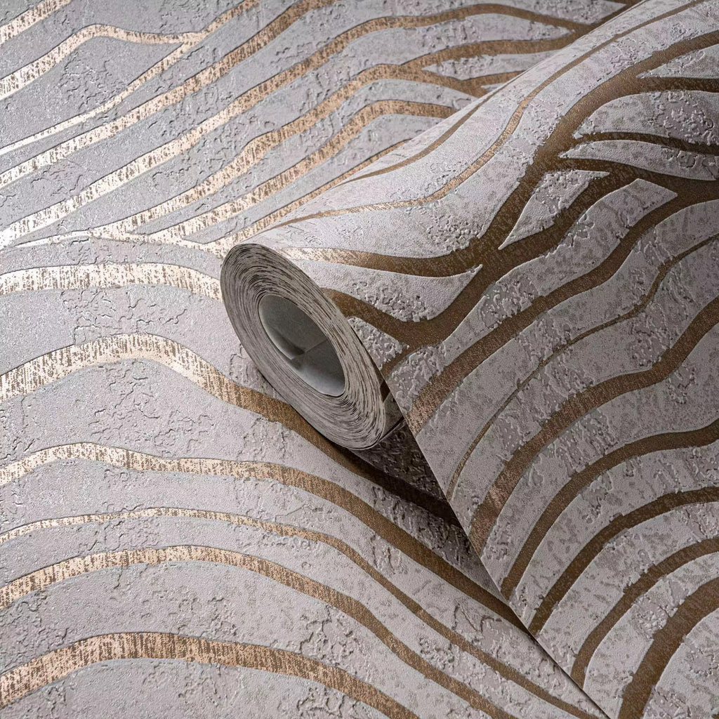 Roll of wallpaper with gold and silver striped pattern on a textured surface