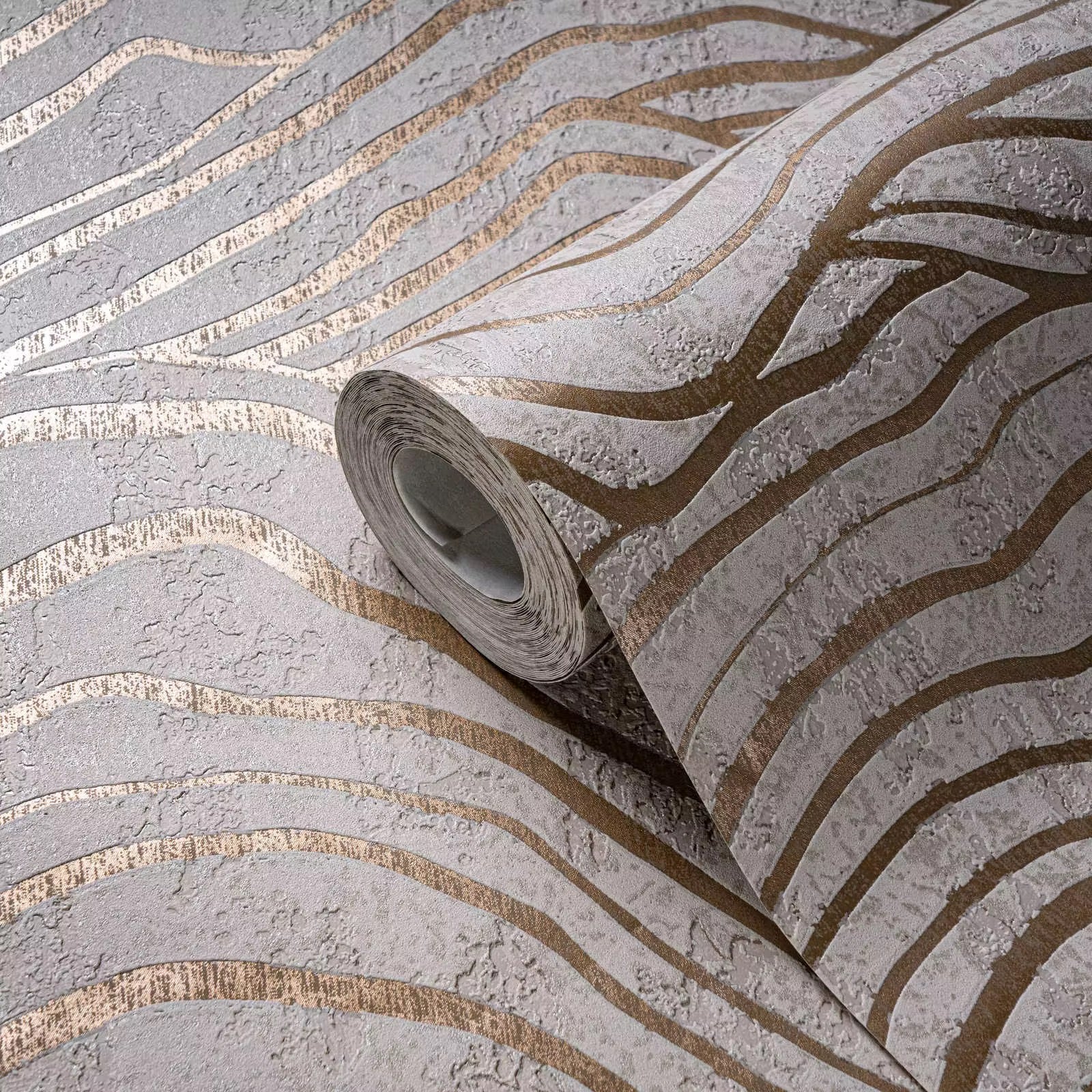 Roll of wallpaper with gold and silver striped pattern on a textured surface