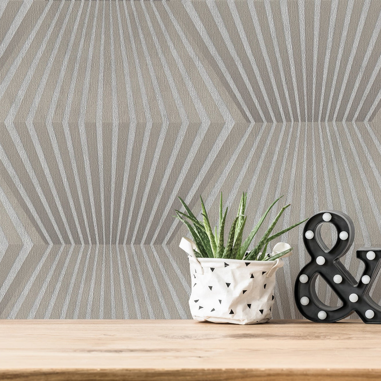 Decorative items on a wooden surface with a geometric patterned wallpaper in the background