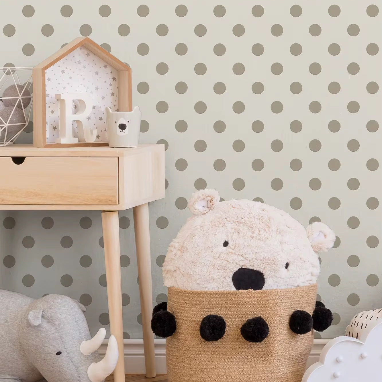 Children's room with a wooden shelf, teddy bear, and polka dot wall.