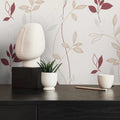 Decorative items on a table with a leaf-patterned wall in the background