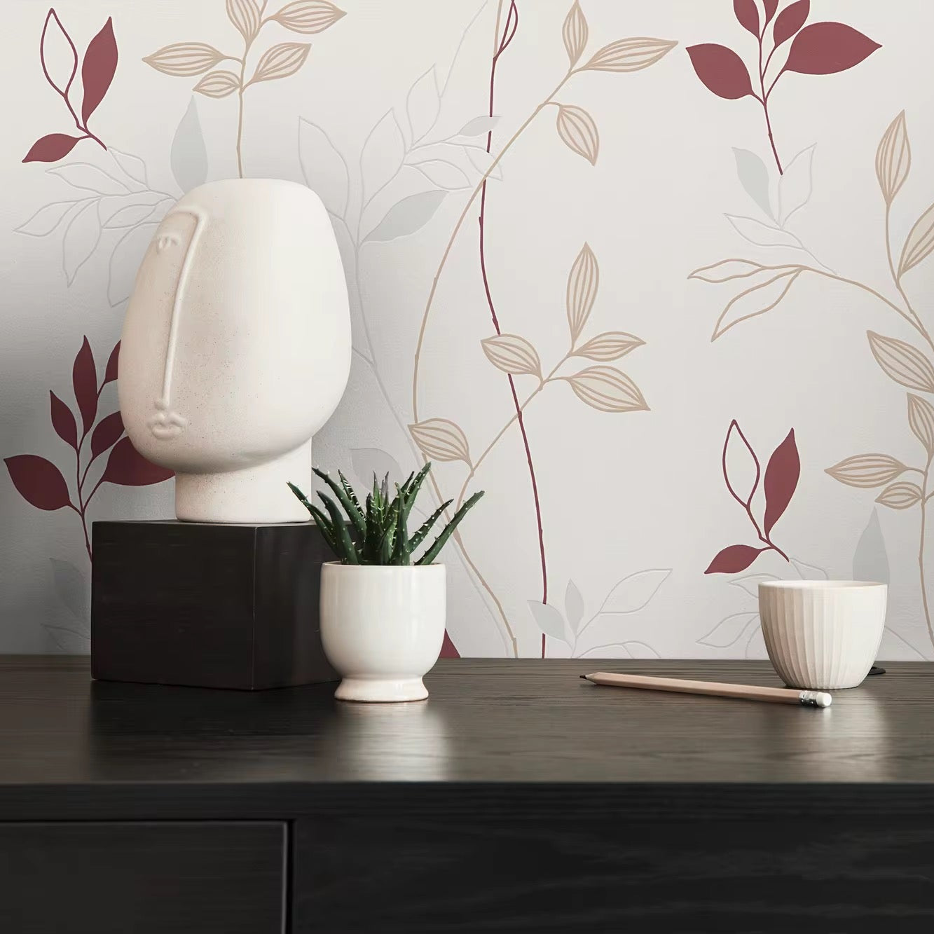 Decorative items on a table with a leaf-patterned wall in the background
